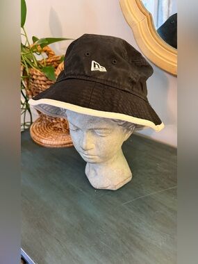 NEW ERA bucket hat with black design with white brim and white NE logo.